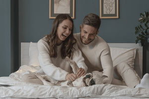 A happy couple with a restless dog in bed