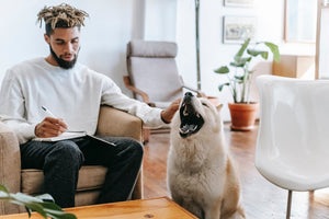 A man sits in a chair next to a howling dog